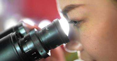 Close up shot, Selective focus eye of professional female veterinarian looking through microscope in laboratory, Smart scientist doing research for biology and medical science of animals video