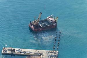 A boat is dredging the sea. Dredging is the removal of sediments and debris from the bottom of lakes, rivers, harbors, and other water bodies. photo