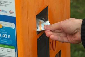 A woman's hand buys a ticket in a ticket machine. photo