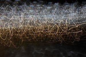 An abstract background with chaotic white and yellow light stripes from a long exposure. photo