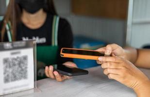 Close up, both hands of a customer holding a mobile phone to scan and transfer payments. photo