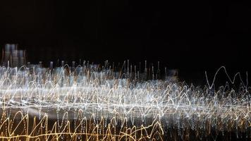 An abstract background with chaotic white and yellow light stripes from a long exposure. photo