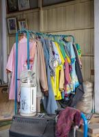 Colorful old clothes are hanging disorderly on iron railings near the cluttered things. photo