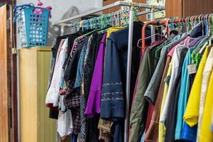 Lots of old, colorful clothes hung chaotically on the iron railings near the closets. photo