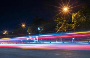 A view from the side of a road where car lights pass by from a long exposure are abstract red-white stripes. photo