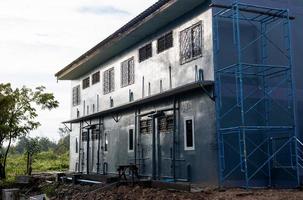 A low angle view of a gray condominium renovated using scaffolding. photo