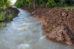 The view of the water rushing through the mounds of soil that have been dug up. photo