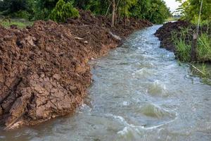 The view of the water rushing through the mounds of soil that have been dug up. photo