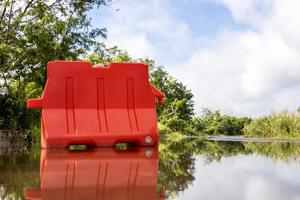 una vista de ángulo bajo de barricadas de plástico naranja colocadas en una carretera inundada. foto