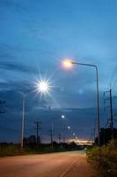 una hermosa vista vertical a la luz de las estrellas de linternas naranjas y blancas al lado de una carretera rural. foto