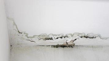 White concrete wall and ceiling background in the corner of the indoor room which has been peeling and damaged. photo