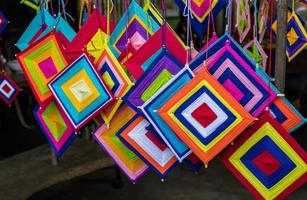 Close-up view of a set of hand-knitted yarn mobiles in a variety of colorful squares hanging. photo