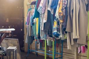 Colorful old clothes are hanging disorderly on iron railings near the cluttered things. photo