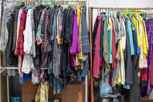 Lots of old, colorful clothes hung chaotically on the iron railings near the closets. photo