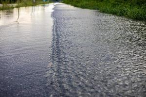 A low angle view of a blurred stream of water crossing an asphalt road. photo