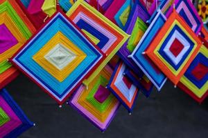 Close-up view of a set of hand-knitted yarn mobiles in a variety of colorful squares hanging. photo