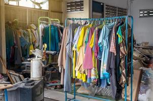 Colorful old clothes are hanging disorderly on iron railings near the cluttered things. photo