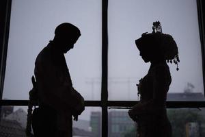 silueta hermosa novia y novio en vestido de novia en una ceremonia de boda tradicional en indonesia foto