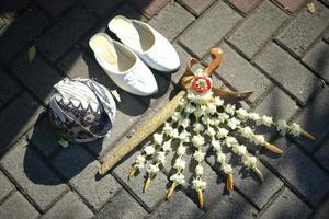 un par de zapatos, tocado y kris o daga ceremonial con collar de flores de jazmín y magnolia para una ceremonia de boda tradicional en indonesia foto