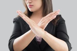 Business woman in black suit showing her denial with no on her hand against gray background photo