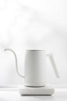 Minimalist white electric kettle on a white table. photo