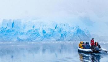 nevadas sobre el barco con turistas congelados conduciendo hacia la enorme pared glaciar azul en el fondo, cerca de almirante brown, península antártica