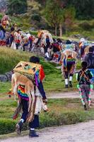 hombre peruano caminando con ropa tradicional con llama muerta en la espalda, ceremonia ritual local, cuzco, perú