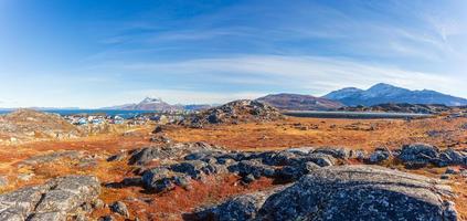 Autumn greenlandic  tundra with orange grass, stones, Inuit settlement and Sermitsiaq mountain in the background, Nuuk, Greenland photo