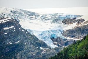 casquete glaciar folgefonna en las montañas con bosque en primer plano, odda, región de hardanger, condado de hordaland, noruega foto