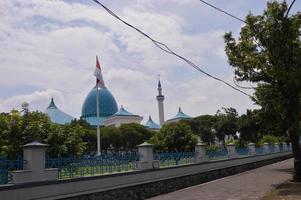 paisaje de una cúpula de mezquita en surabaya con árboles y banderas ondeando en postes foto