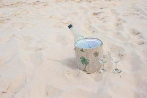 Bottle of wine and two glasses on sandy beach photo