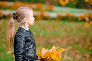 retrato de niña adorable con ramo de hojas amarillas en otoño en scooter foto