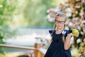 adorable colegiala con manzana verde al aire libre. concepto de regreso a la escuela foto