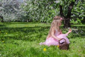 linda niña recogiendo flores en el floreciente huerto de manzanas en un día soleado foto