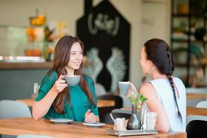 Happy smiling young women with coffee cups at cafe. Communication and friendship concept photo