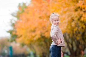 Portrait of adorable little girl with yellow trees background in fall photo