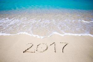 2017 handwritten on sandy beach with soft ocean wave on background photo