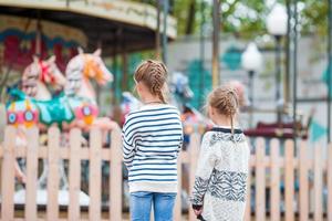 Adorable little girls near the carousel outdoors photo