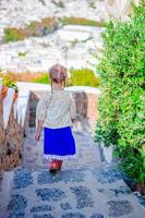 Adorable girl at street of typical greek traditional village on Mykonos Island, in Greece photo