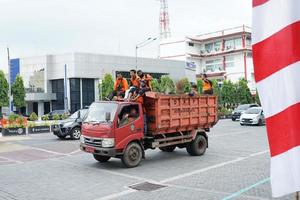 SOLO, INDONESIA - JUNE 9, 2022 Garbage pick-up cars, trash can workers cleaning the city on the highway photo