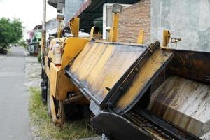 acabadora de asfalto, detalle frontal de la máquina de construcción de carreteras de asfalto amarillo estacionada al lado de la carretera foto