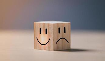 cara sonriente en el lado brillante y cara triste en el lado oscuro en un cubo de bloques de madera para una selección de mentalidad positiva. concepto de salud mental y estado emocional.