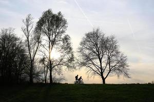 silhouette of people riding the bike on a rural road at sunset along Danube river in Regensburg, Germany, Europe. photo