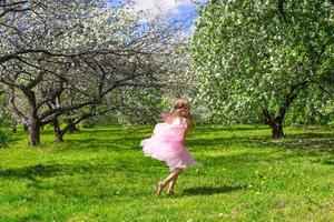 Adorable little girl with butterfly wings have fun in blossoming apple orchard photo