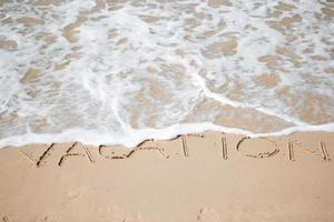 Vacation written on tropical beach white sand photo