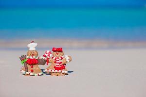 galletas de hombre de pan de jengibre de navidad en una playa de arena blanca foto