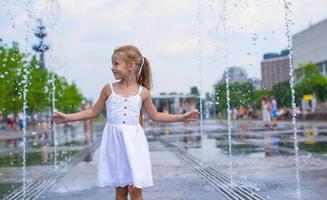 una niña feliz se divierte en una fuente al aire libre en un día caluroso foto