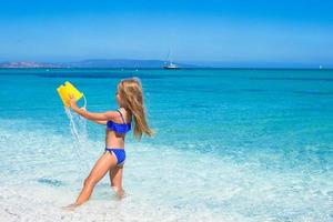 Adorable little girl have fun in shallow water at tropical beach photo