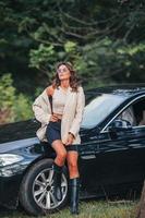 Young woman outdoors standing by her black car photo