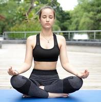 Beautiful woman practicing yoga outdoor in the tranquil nature park. Female person leisure activity is meditation, relaxation mindfulness exercise for healthy lifestyle and peaceful spirituality. photo